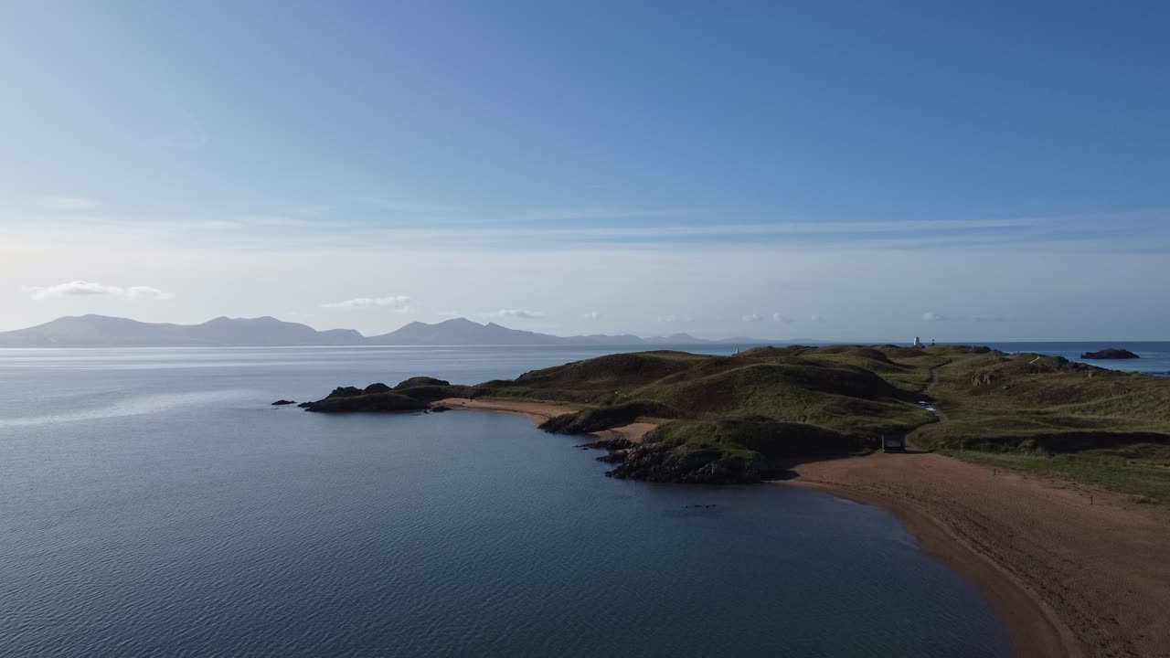 태양이 떠오르는 아일랜드 해를 가로질러 흐릿한 스노우도니아 산맥과 함께 이 랜드드윈 해변을 바라보는 공중 전망