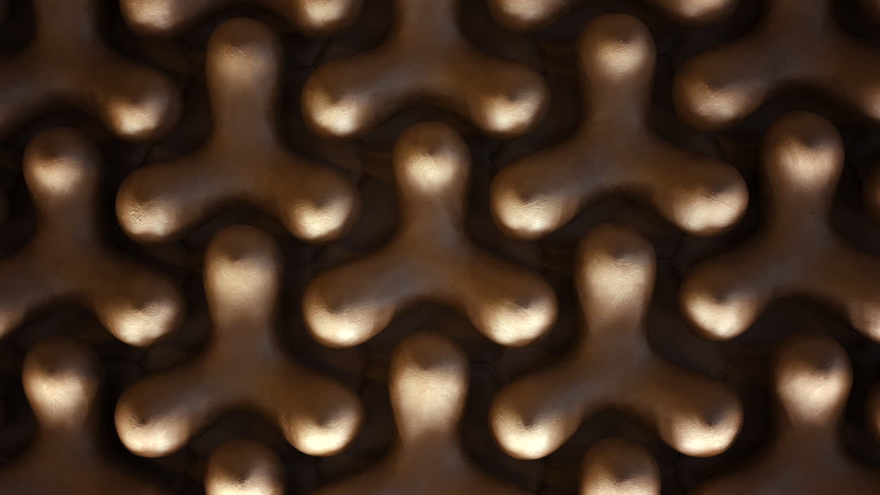 Primo piano di una superficie decorativa con motivo geometrico dorato che crea forme e texture ripetute.
