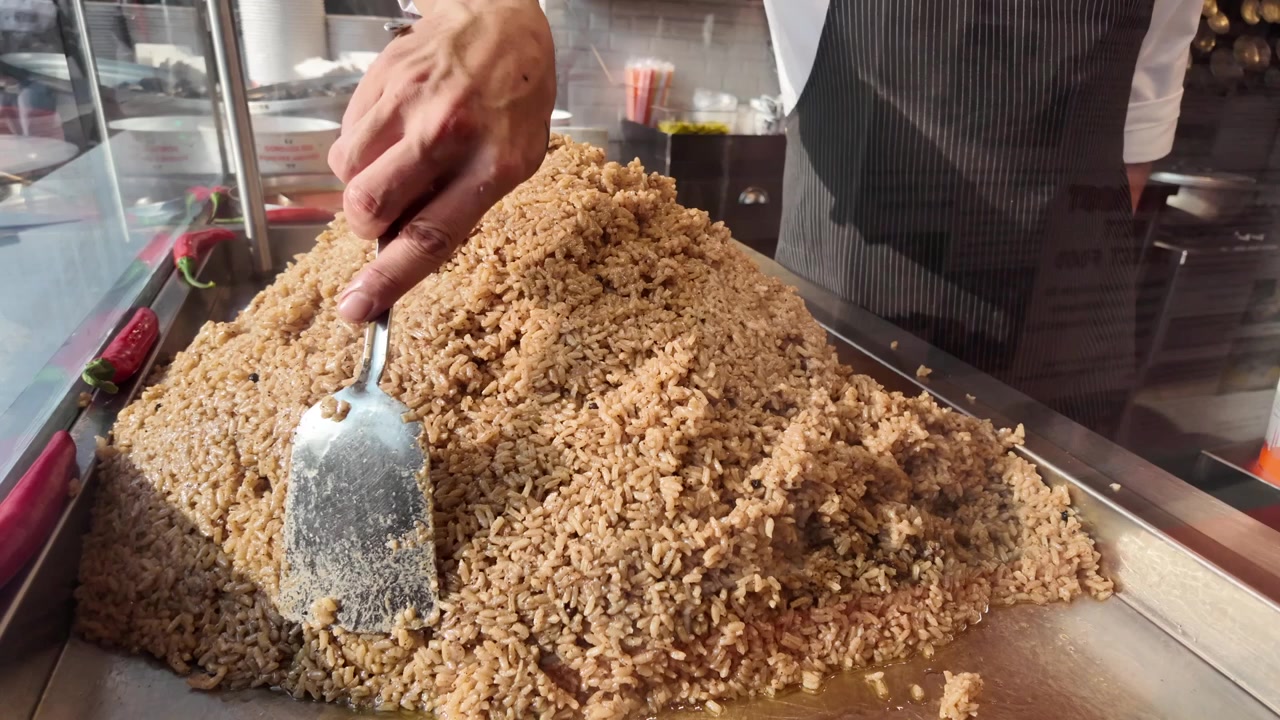 Chef Preparing Large Pile of Cooked Rice in Restaurant Kitchen