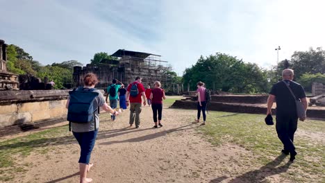group of tourists leisurely walks towards scaffolded thuparamaya temple, enjoying the warm sunny weather.