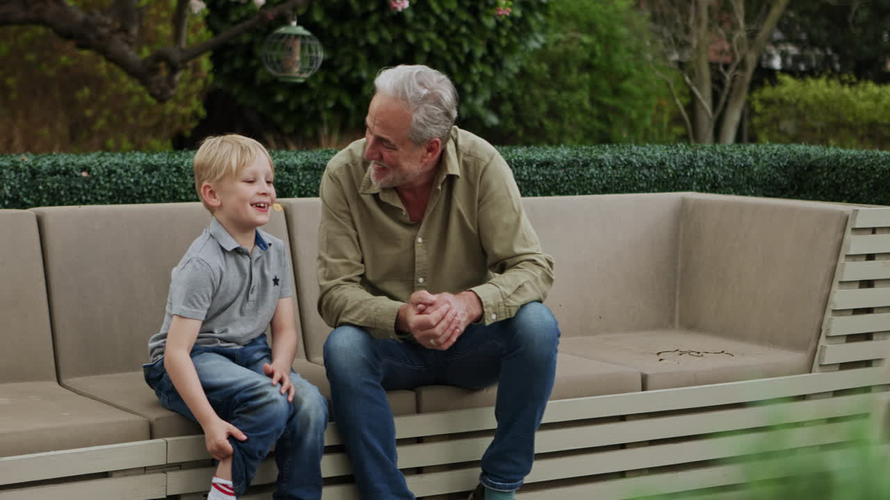 A boy and his grandfather sitting on a couch outdoors