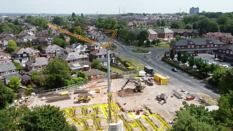 tall crane setting building foundation in british town neighbourhood aerial view above suburban townhouse skyline