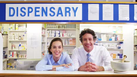 smiling pharmacists leaning at counter in pharmacy