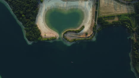 aerial view of heart-shaped lake with beach and people