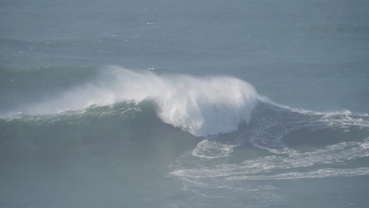 Enormous waves crash on the coast of Nazaré, Portugal, with surfers tackling the mighty surf