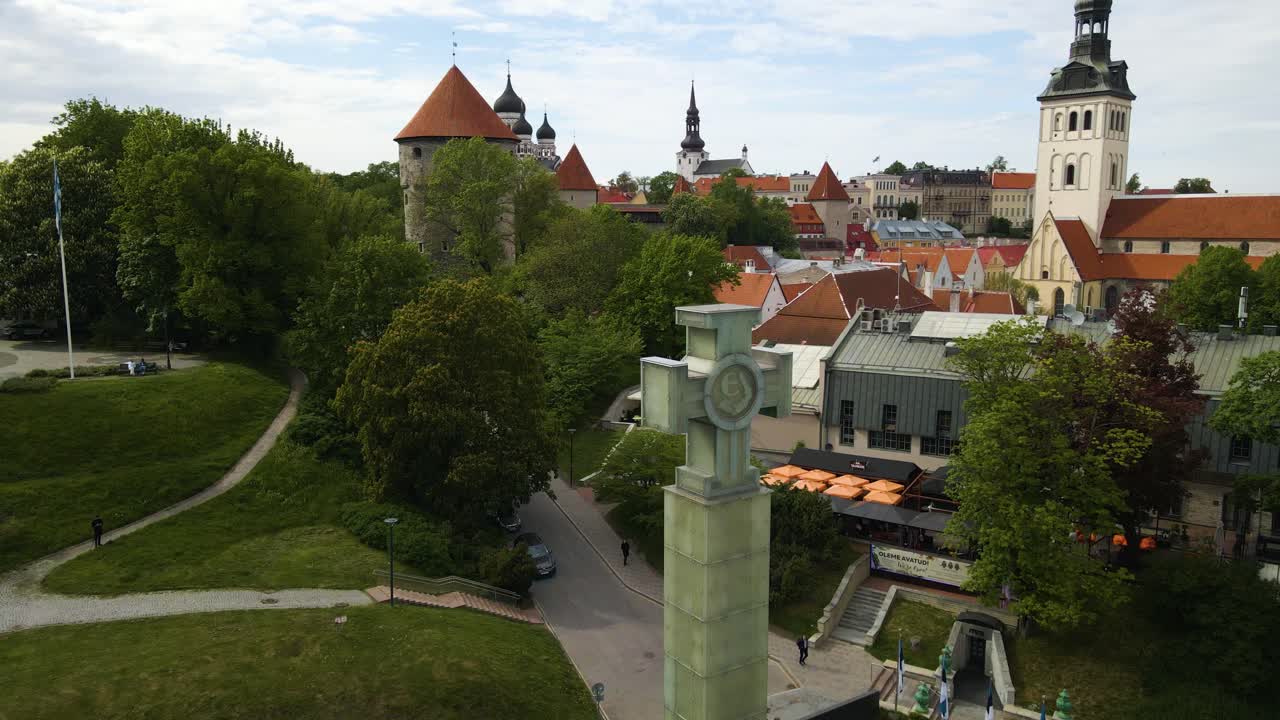 Great aerial view over Cross of Liberty monument and behind postcard view of the old town with medieval buildings and churches. Hilltop park designed as city green space during beautiful summer day