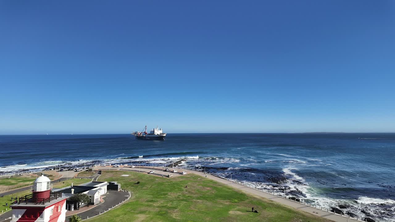 Time lapse aerial view of Green Point Lighthouse and a ship offshore, Cape Town, South Africa.