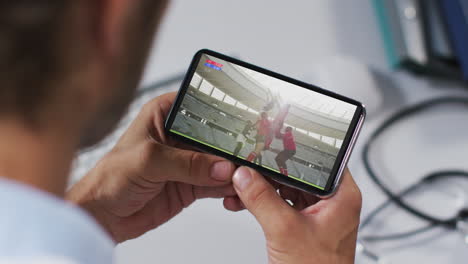 composición de un médico masculino viendo un partido de rugby en un teléfono inteligente