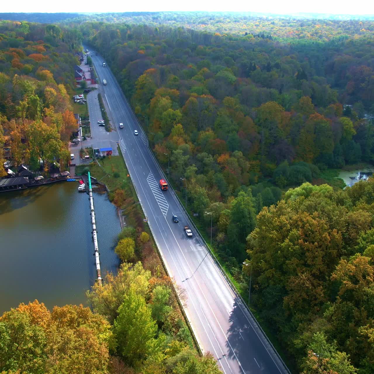 Endless forest crossed by the narrow river and high speed road. Motorway going along the camping site area. Top view