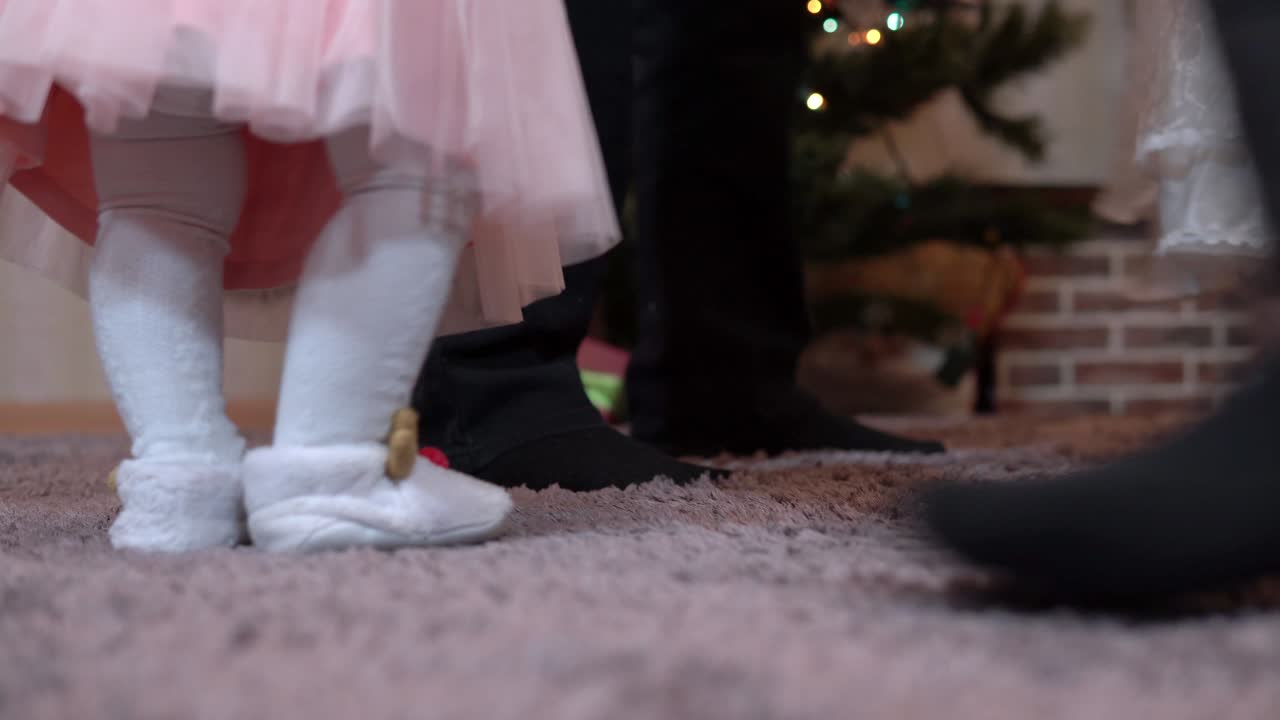 piernas de primer plano de una familia dando vueltas en un baile redondo para navidad en el árbol de navidad. abuelos y nietas celebran el año nuevo