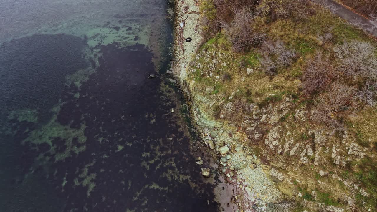 Aerial view of a rocky shoreline next to calm waters