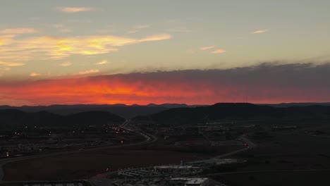 Establishing-aerial-over-Rapid-City,-South-Dakota-during-a-warm-orange-and-red-sunset