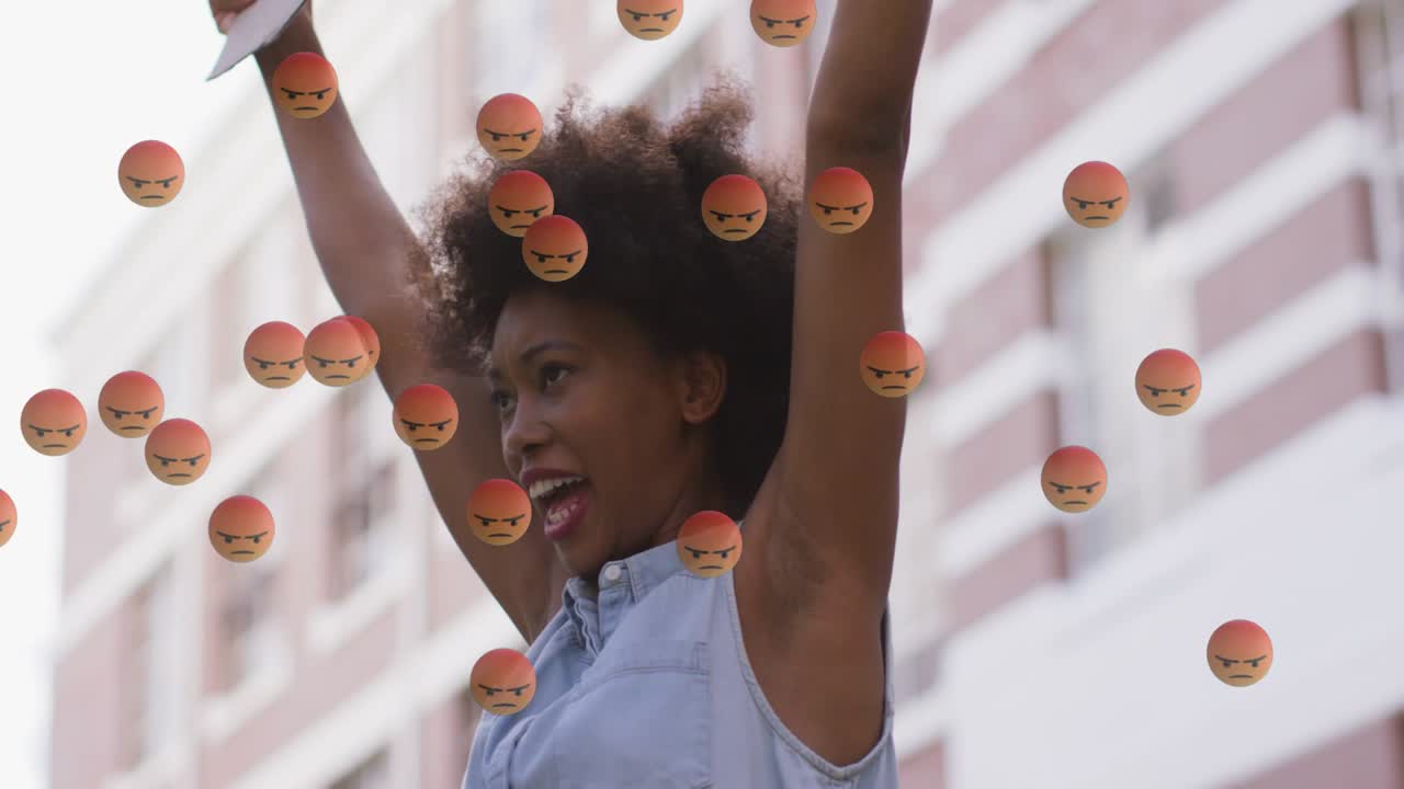 Woman raising sign by brick building sparking angry emojis masking, showing face in media protest