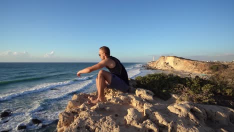 young alone man with sunglass looks thoughtfully at the ocean