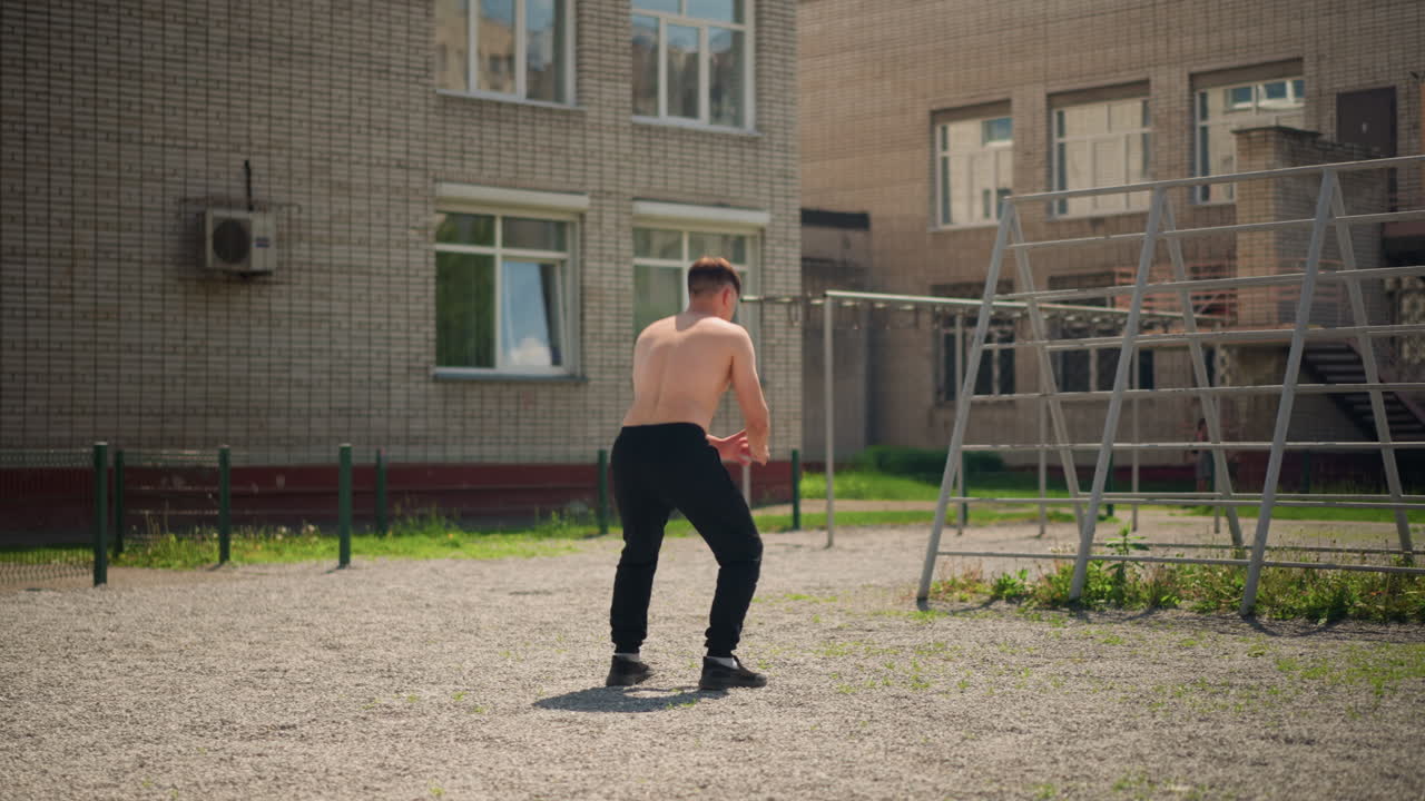 hombre haciendo sentadillas con salto explosivo en el exterior; hombre realizando ejercicios pliométricos vigorosos en un día de verano; hombre ejecutando sentadillas con salto de alto impacto en un parque residencial durante el día
