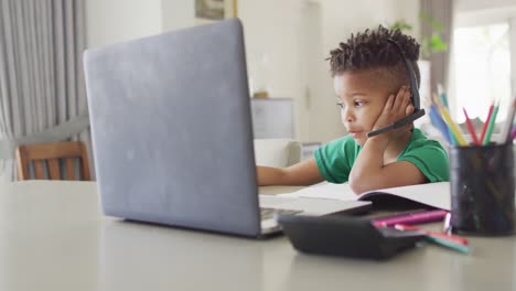 Feliz-Niño-Afroamericano-Sentado-En-La-Mesa,-Usando-Una-Computadora-Portátil-Para-Clases-En-Línea