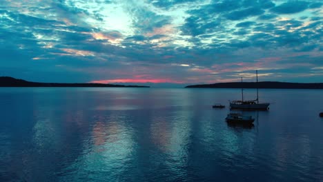 majestic colorful sky after sunset and anchored boats in twilight by coast of exotic tropical island