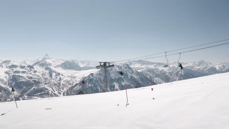 Skilift-Hoch-In-Den-Bergen,-Der-Im-Winter-Von-Drohne-Erfasst-Wird,-Mit-Skifahrern,-Die-An-Der-Spitze-Fahren