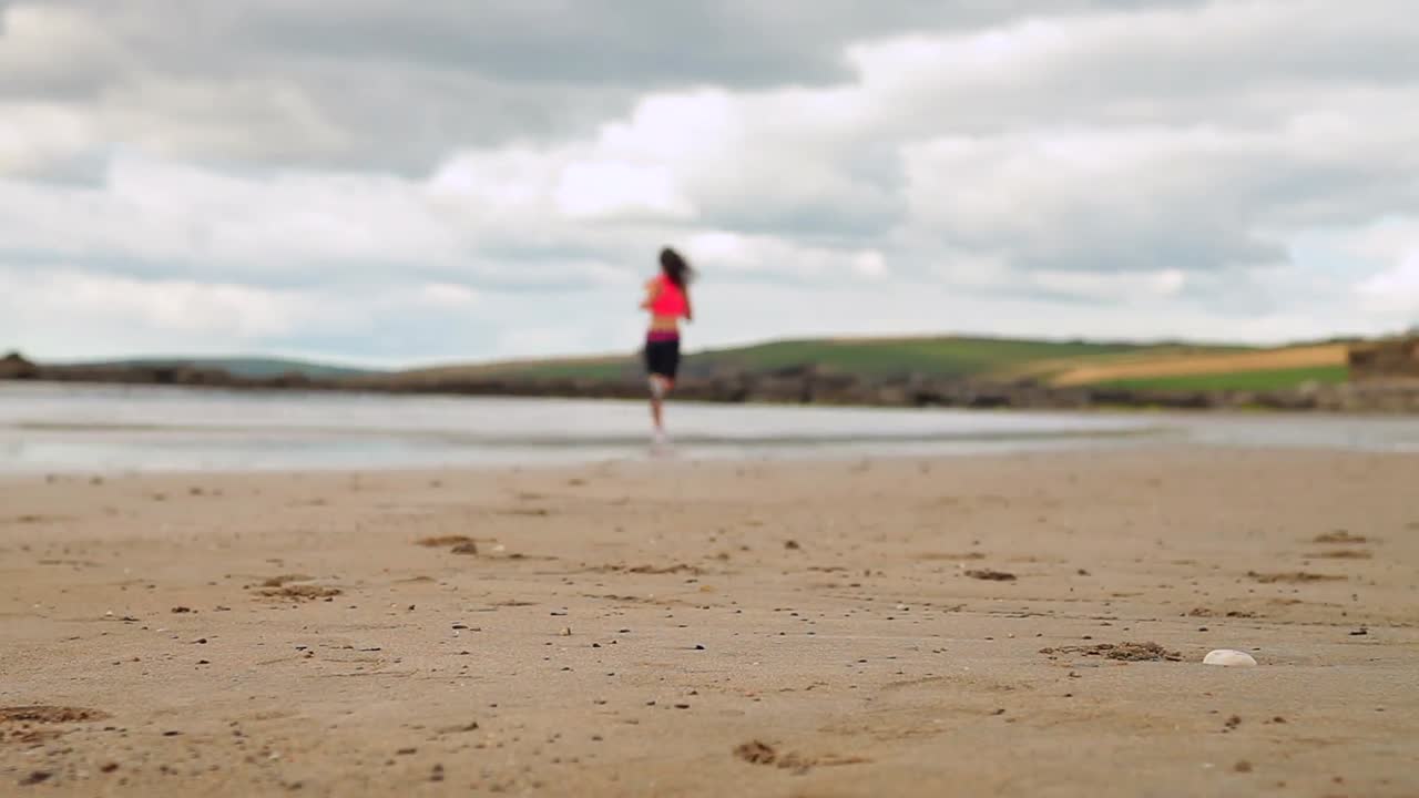 bruneta atlética corriendo en la playa