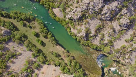 Kayaks-paddling-towards-small-waterfall-at-zrmanja-river-Croatia,-aerial