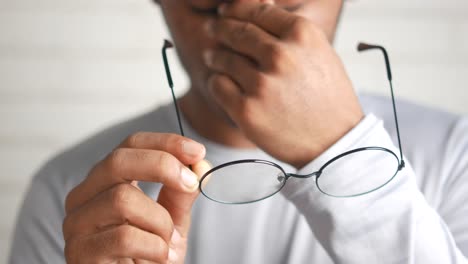 man covering mouth with hands while holding glasses