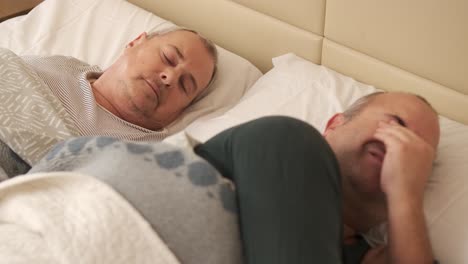 mature gay couple waking up in bed in the morning