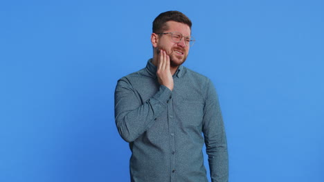 man in glasses touching cheek closing eyes with expression of terrible suffer from painful toothache