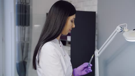 an experienced cosmetologist in gloves holds a syringe with an injection for a cosmetic procedure and checks it. modern methods of aesthetic medicine