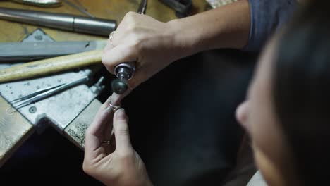 close up of hands of caucasian female jeweller using tools, making jewelry