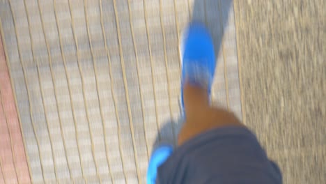 male feet in blue shoes walking on street