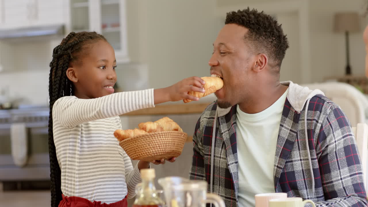 Happy african american father and daughter having breakfast at home, slow motion