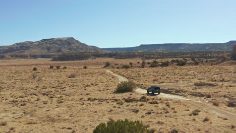 fast moving aerial following car down remote dirt road in open desert