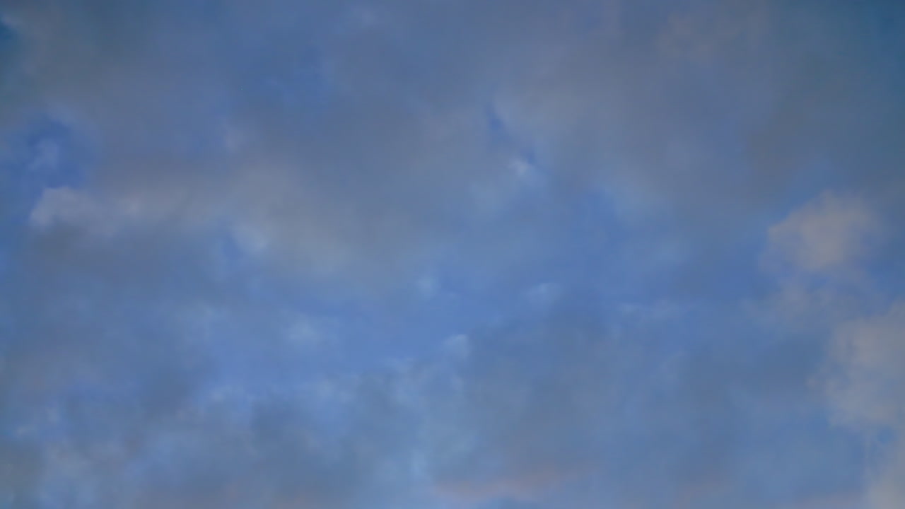 Peaceful view of evening sky with scattered clouds illuminated by soft fading sunlight creating serene blue and gray gradient, showcasing natural beauty and calmness during twilight hour