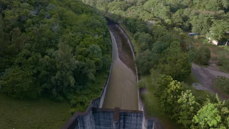Drone dolly-in over Hatillo Dam spillway, surrounded by lush greenery in Cotuí, Dominican Republic