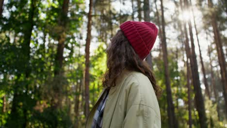 woman in a red hat looking up in a forest