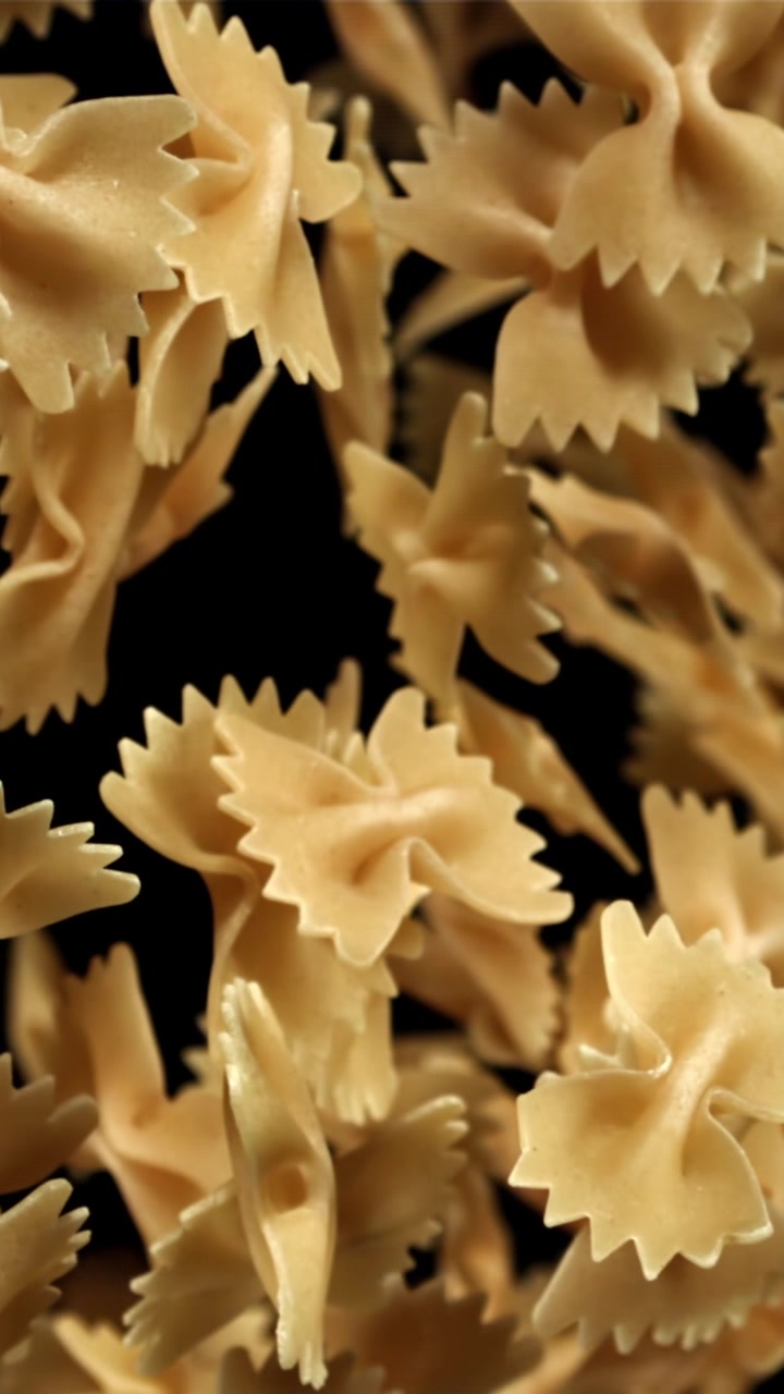 Pasta farfalle cruda che cade al rallentatore su sfondo nero