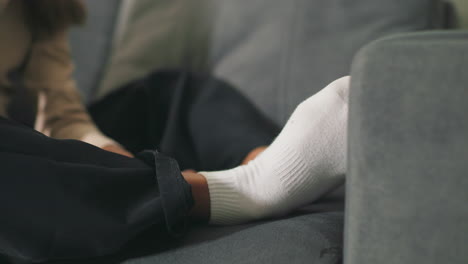 close-up of girl’s feet in white socks resting on couch. cozy indoor moment, relaxed posture, focusing on comfort and calm at home, creating peaceful, domestic atmosphere