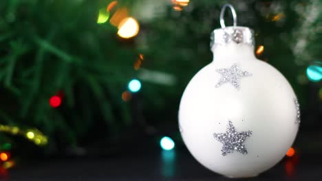luces parpadeantes coloridas detrás de un pequeño ornamento navideño blanco para el árbol de navidad
