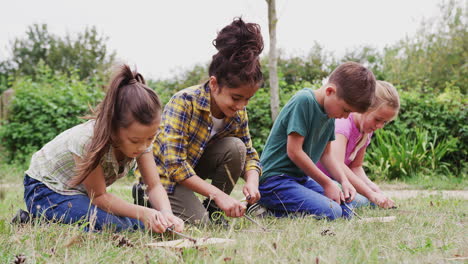 group of children on outdoor camping trip learning how to make fire