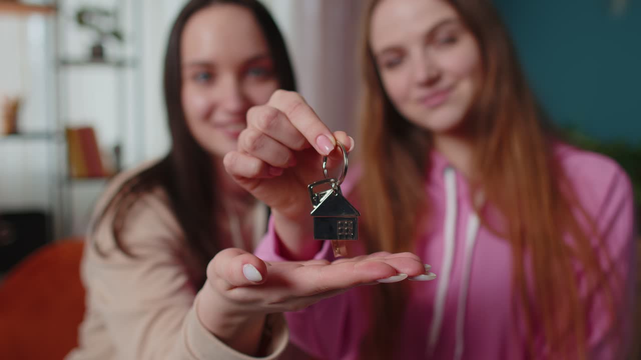 Girls siblings homeowners hugging and showing new home apartment keys receiving mortgage loan