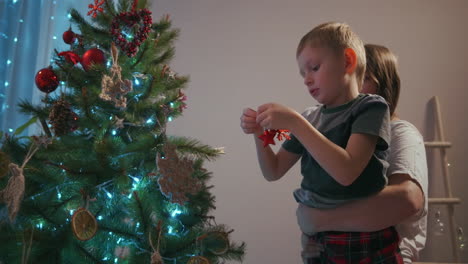 Una-Madre-Recoge-A-Su-Hijo-Para-Decorar-Un-árbol-De-Navidad.-Decoraciones-De-Año-Nuevo-Y-Preparación-Para-La-Navidad.-Imágenes-4k-De-Alta-Calidad