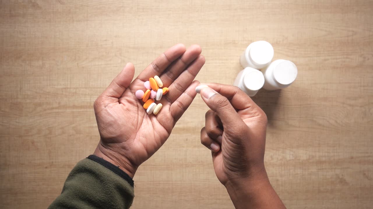 Hand holding colorful pills and medicine bottles on a table