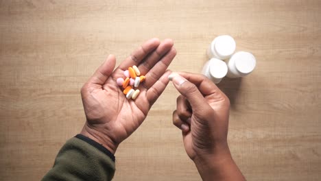 hand holding colorful pills and medicine bottles on a table