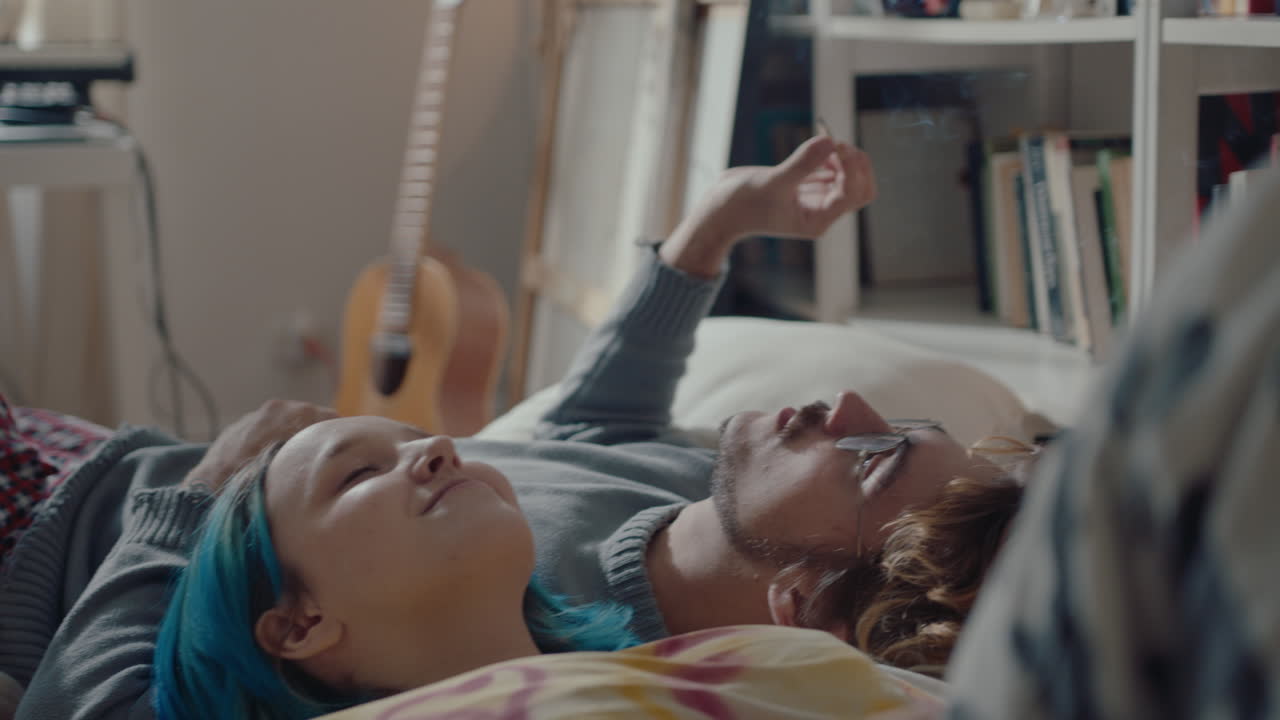 Young Romantic Couple Smoking a Cigarette Together on Bed
