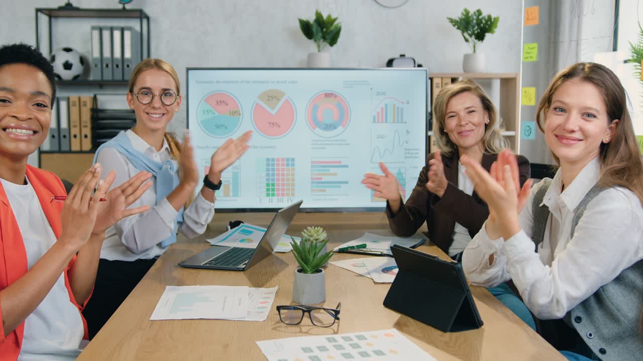 Concetto di successo e fortuna, con un gruppo multietnico di donne d'affari attraenti, felici, sorridenti ed esperte che applaudono durante una riunione congiunta in ufficio.