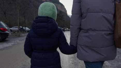 mother and daughter holding hands while walking in snowy mountains