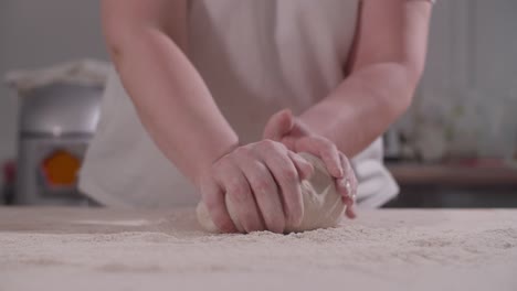 female hands knead and toss dough on kitchen