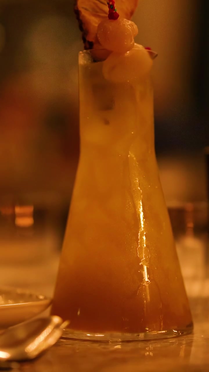 Un vivace cocktail tropicale guarnito con frutta, ambientato in un ambiente illuminato caldamente, che mostra un'atmosfera rilassata e invitante
