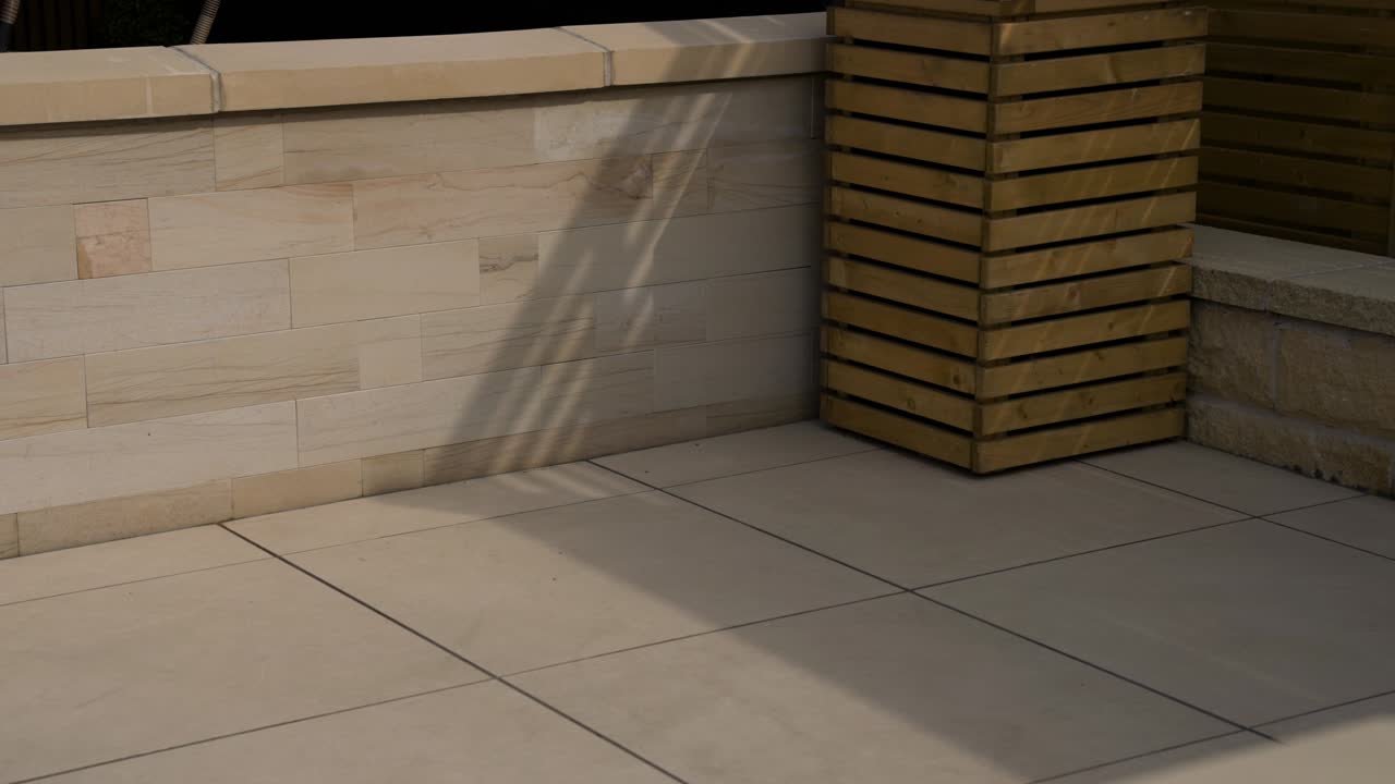 la luz de la tarde golpeando suavemente las piedras de pavimento de lujo en el jardín trasero en el día de verano con un montón de blancos suaves losas de arena amarilla y beige