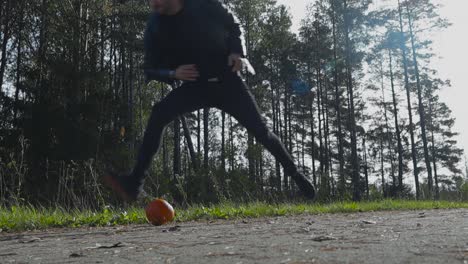 person or a man throwing a halloween pumpkin to the ground and destroying, smashing it in slow motion during autumn or late summer during holidays.day time with cloudy weather and trees in the back.